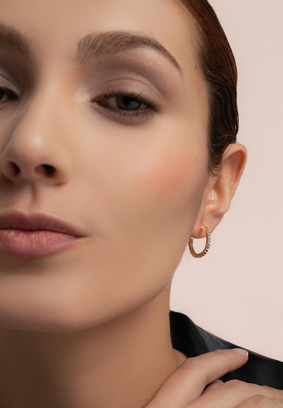 Modelo utilizando Aritos dorados brillantes con circonitas en blanco
