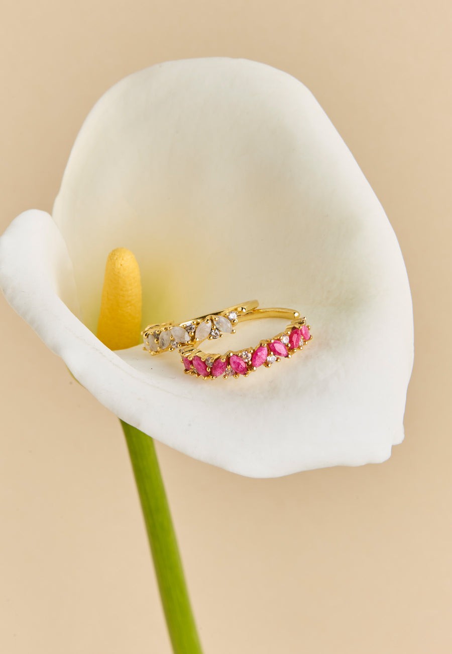 Anillo dorado birthstone Abril con piedra de nacimiento Topacio, colocado sobre una flor de cala blanca, joya delicada para novia o regalo personalizado.