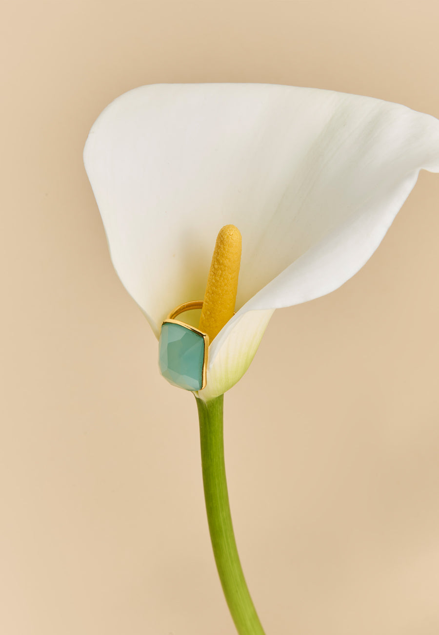 Anillo dorado Stardust con piedra de aguamarina de Lavani Jewels colocado en el centro de una cala blanca, destacando su diseño delicado y brillante.