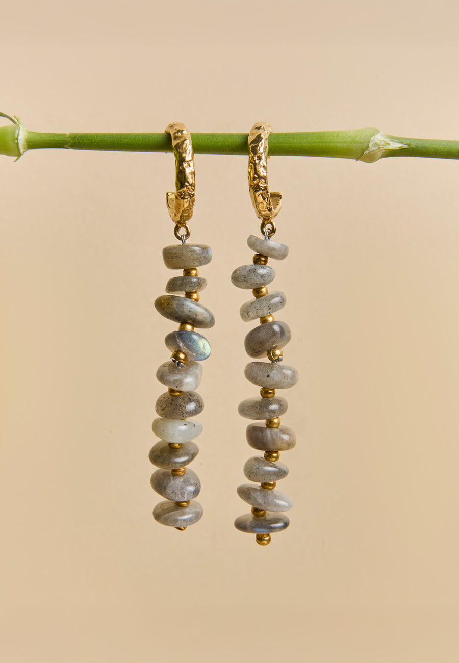 Aros Mizu Gris con piedras de labradorita y detalles dorados colgando de una rama, diseño exclusivo de Lavani Jewels.
