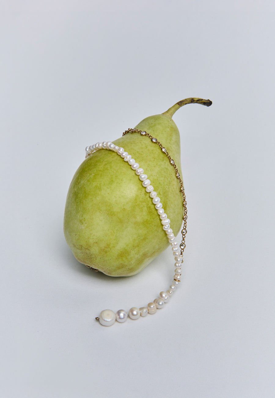 Collar de perlas Celine de Lavani sobre pera verde, joya elegante ideal para una novia clásica.