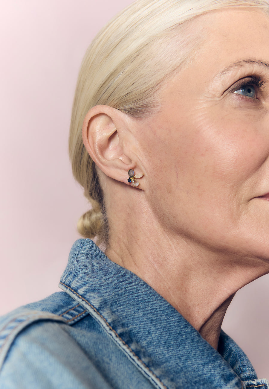 Primer plano del rostro de una mujer rubia con chaqueta vaquera luciendo los pendientes dorados con forma de abeja Cinema de Lavani Jewels.