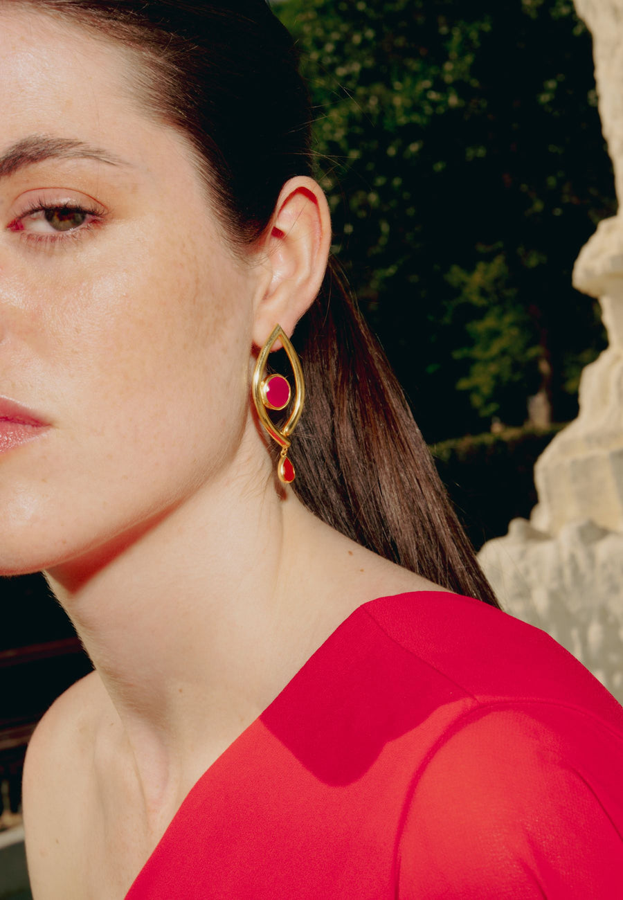 Modelo con pendientes de tercer ojo en tonos rojizos