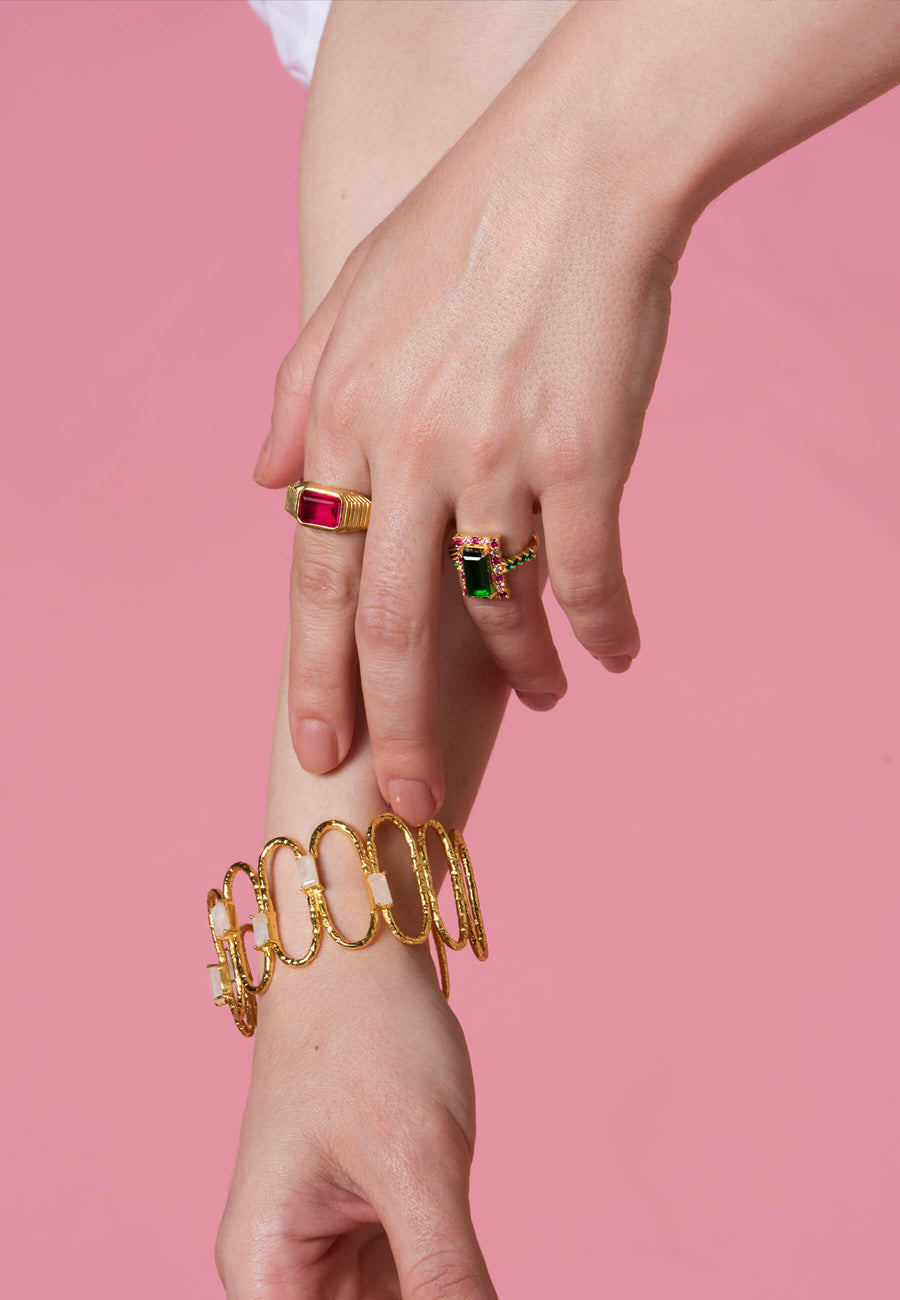 Anillo chevalier con piedra fucsia y baño de oro combinado con pulsera y anillo verde