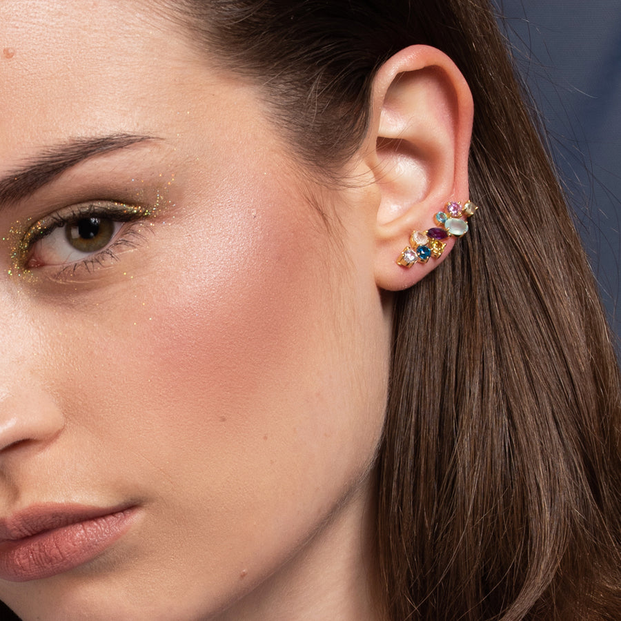 Chica con pendientes trepadores grandes formados por piedras naturales que recorren el lóbulo de su oreja.