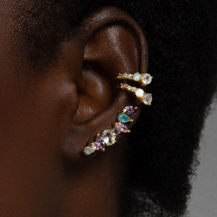 Chica con pendientes trepadores de mujer formado por piedras naturales con tonalidad pastel y bañados en oro.