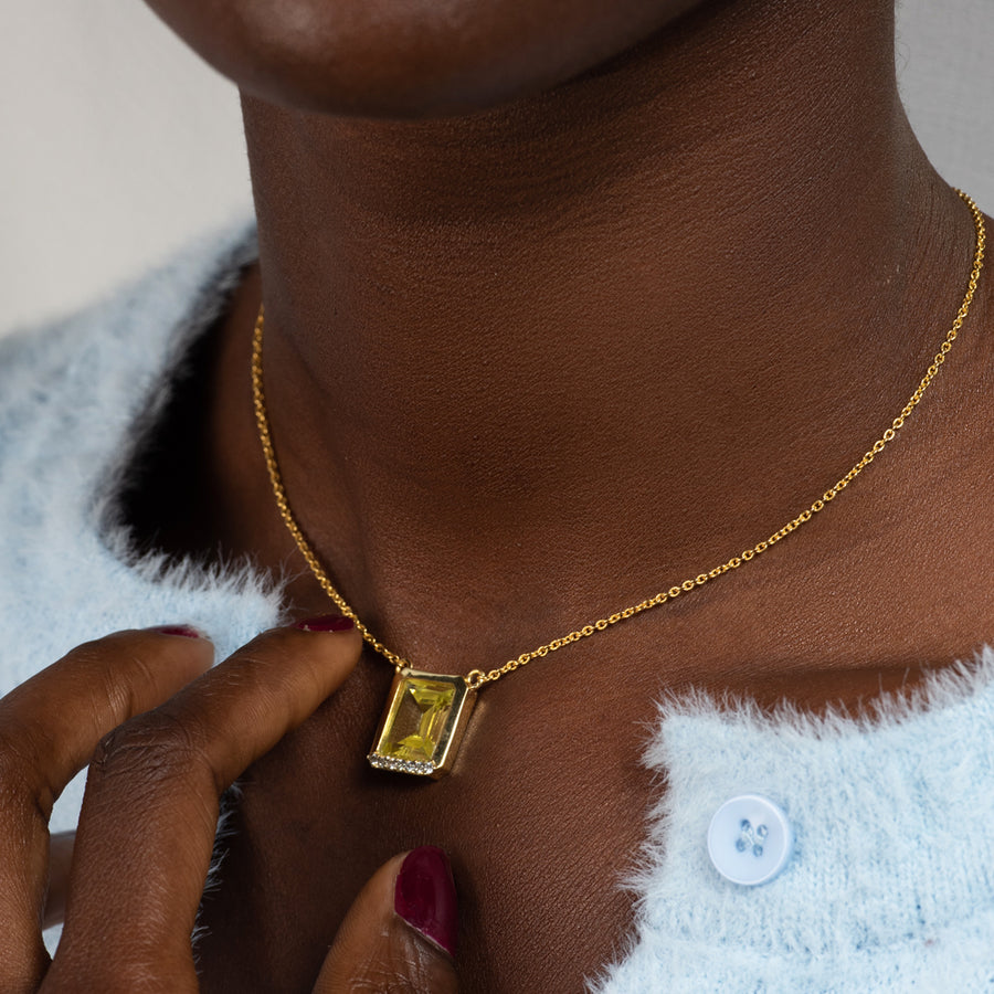 Mujer con colgante decorado con piedras naturales verdes y blancas y un acabado en oro de 22k.