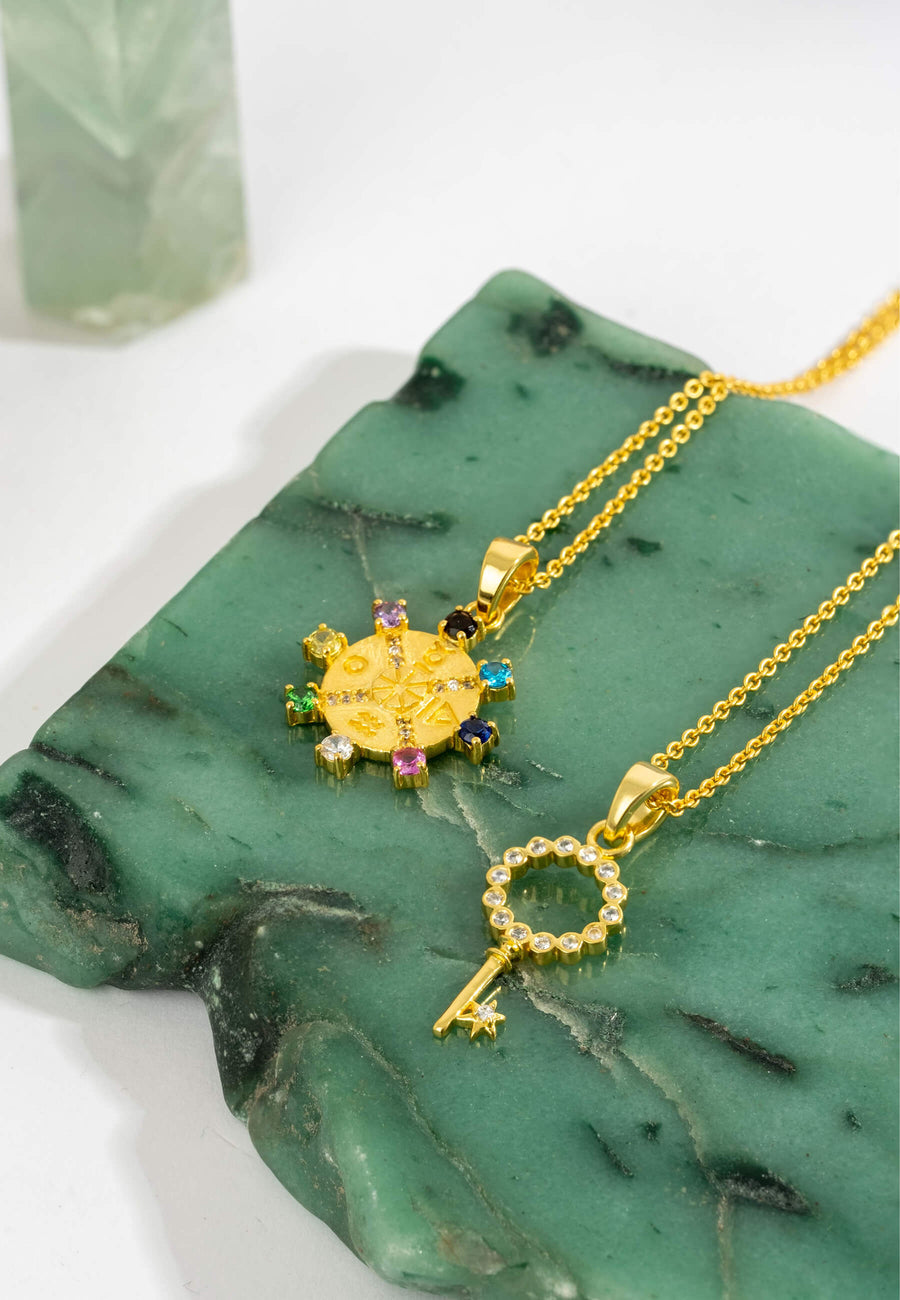 collar rueda de la fortuna dorado junto a colgante de llave bañados en oro de 18 quilates