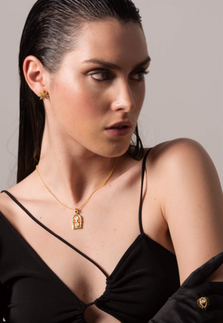 modelo con collar de reloj de arena y pendientes de estrella dorados bañados en oro de 18 quilates