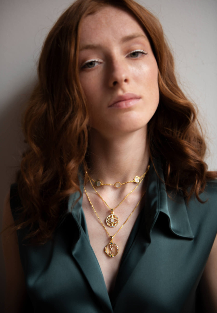 collar de ojo turco combinado con colgante de infinito y choker de fases lunares para un look de layering dorado