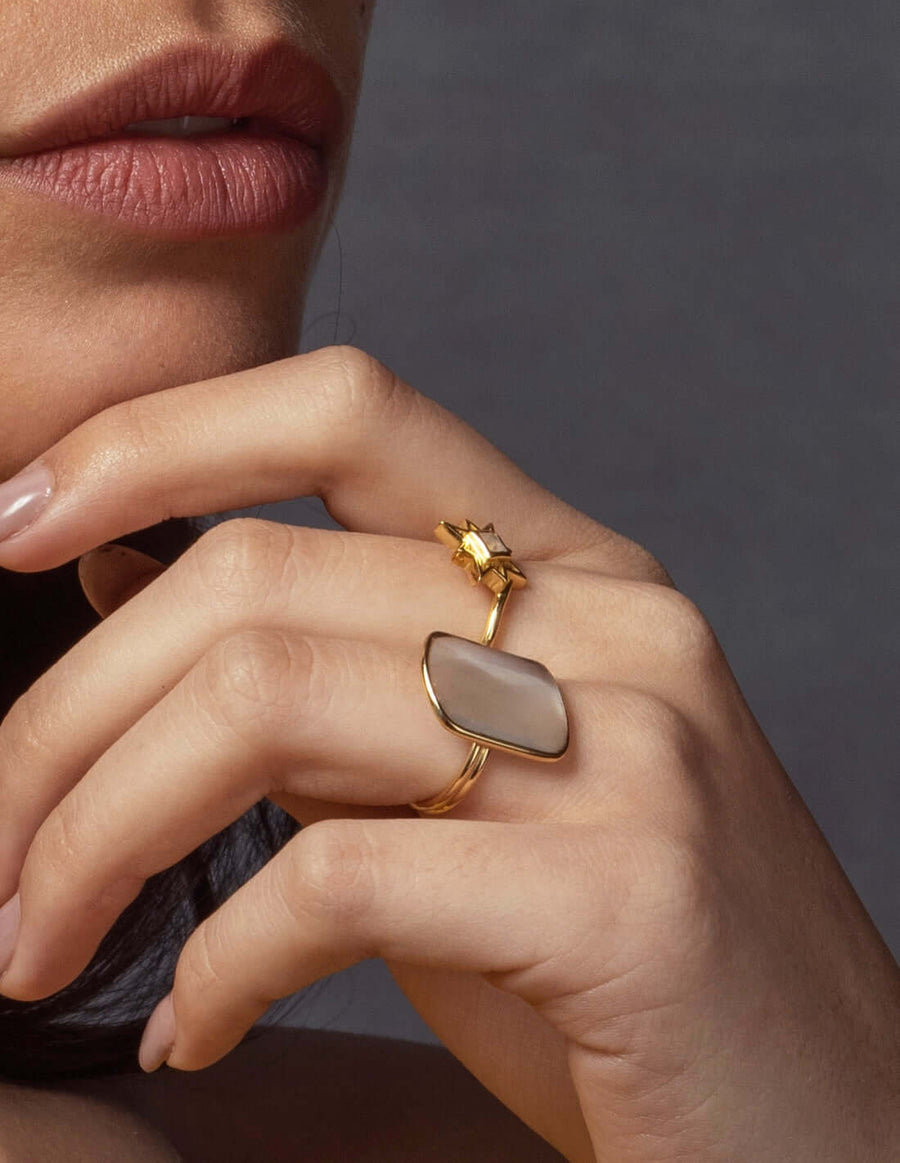 Modelo luciendo anillos bañados en oro y con piedras naturales semipreciosas en tonos blancos