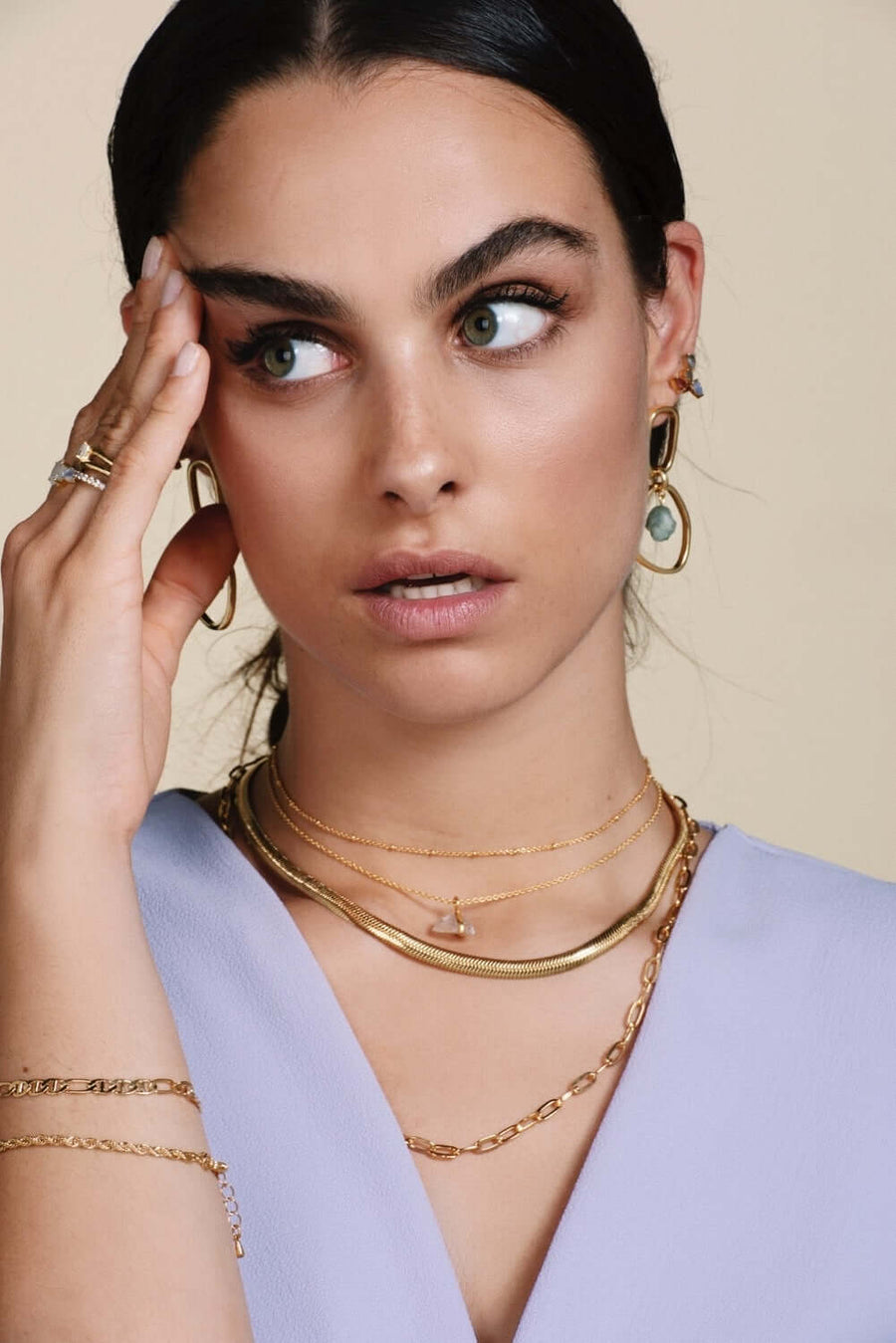 Modelo con joyas bañadas en oro y collares estilo cadena y choker de bolitas dorado