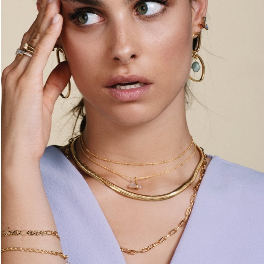 Modelo con cadenas doradas de eslabones y pendientes dorados