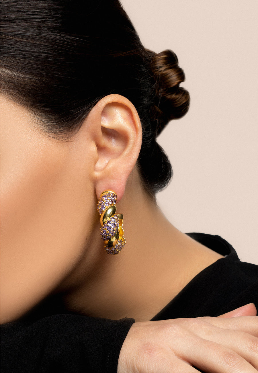Detalle de Pendientes tipo aros entrelazados morados con piedras circonitas y baño de oro