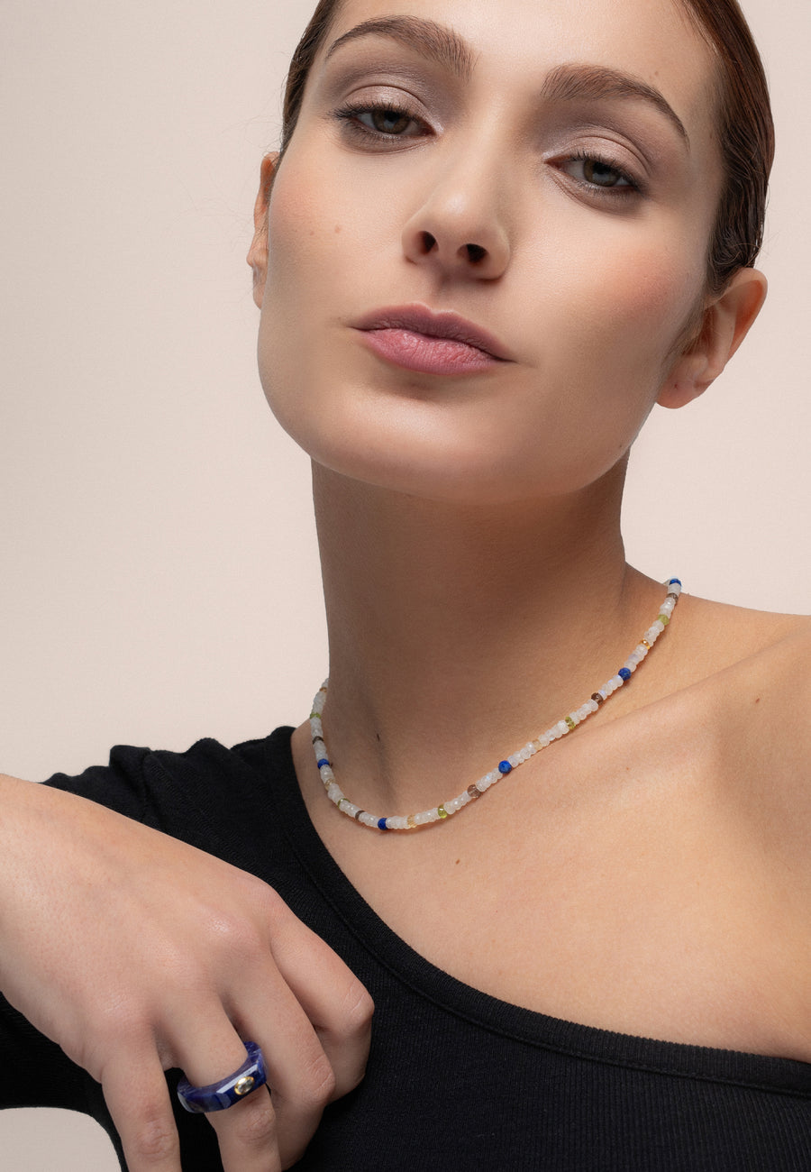 Modelo utilizando el collar de Piedra Luna de colores hecho con cuentas de la piedra Luna blanca combinado con anillo azul