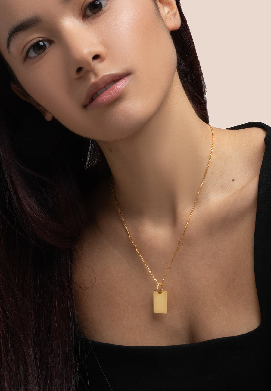 Chica morena utilizando el colgante rectangular dorado grabable de Lavani Jewels