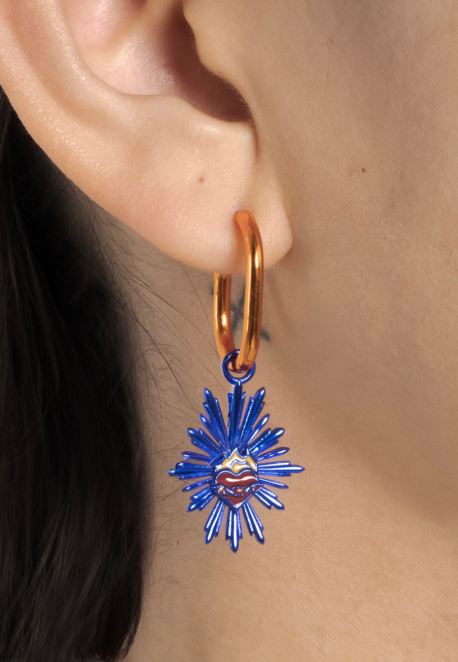 Charm de escapulario azul en aros naranjas puestos en la oreja