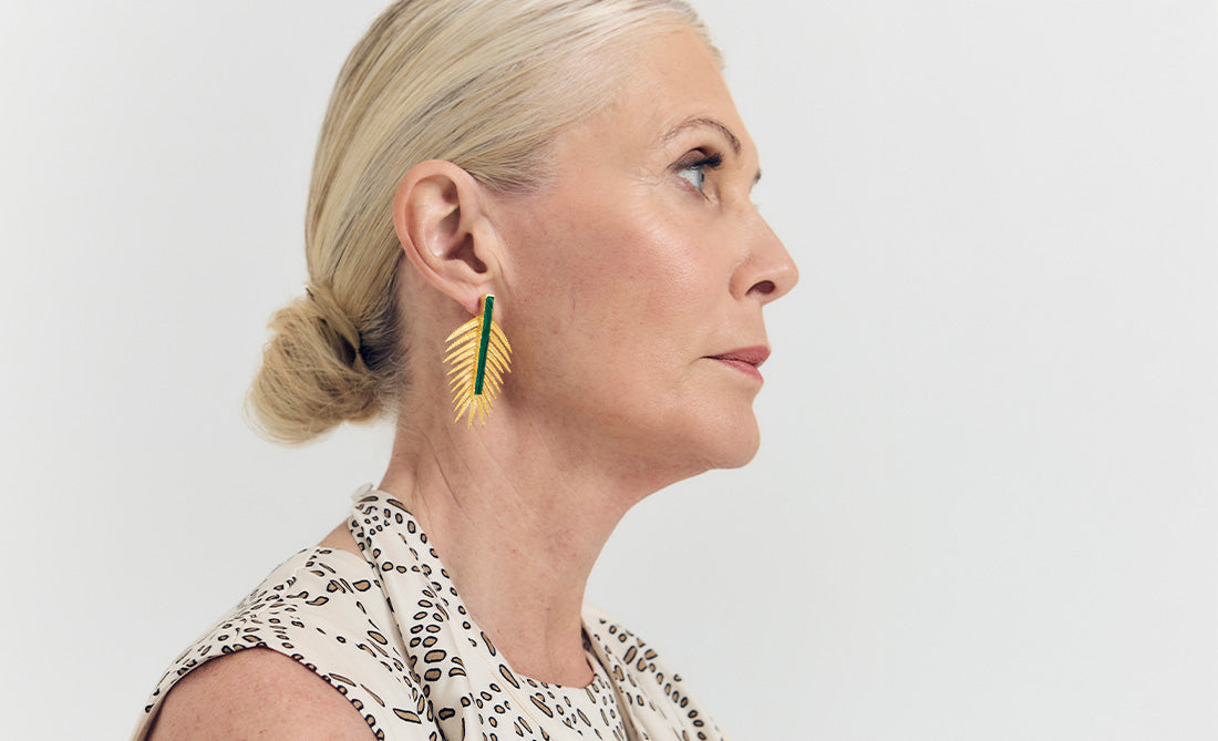 Pendientes dorados grandes con forma de hoja y detalle verde, diseño original para mujer y ocasiones especiales.