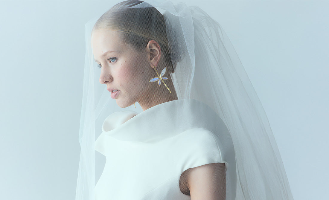 Pendientes dorados grandes en forma de flor blanca, ideales para novias que buscan un look elegante y original en su boda.