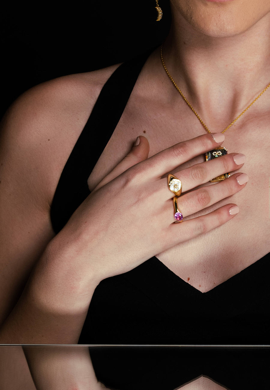modelo con combinación de joyas formada por anillo de sello dorado y blanco y anillo de sello rosa con colgante de carta del tarot
