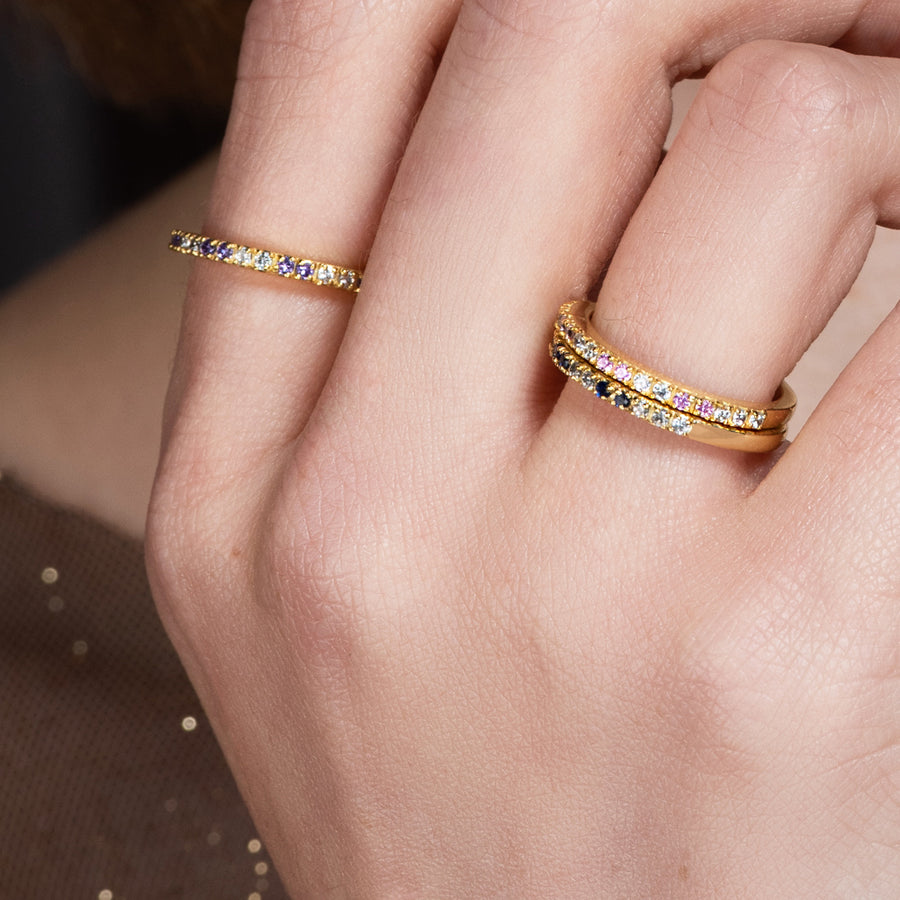 Mano de mujer con 3 anillos sencillos adornados con circonitas de varios colores.