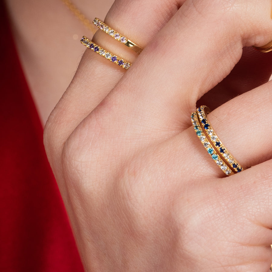 Mano de mujer con set de anillos minimalistas decorados con piedras naturales.