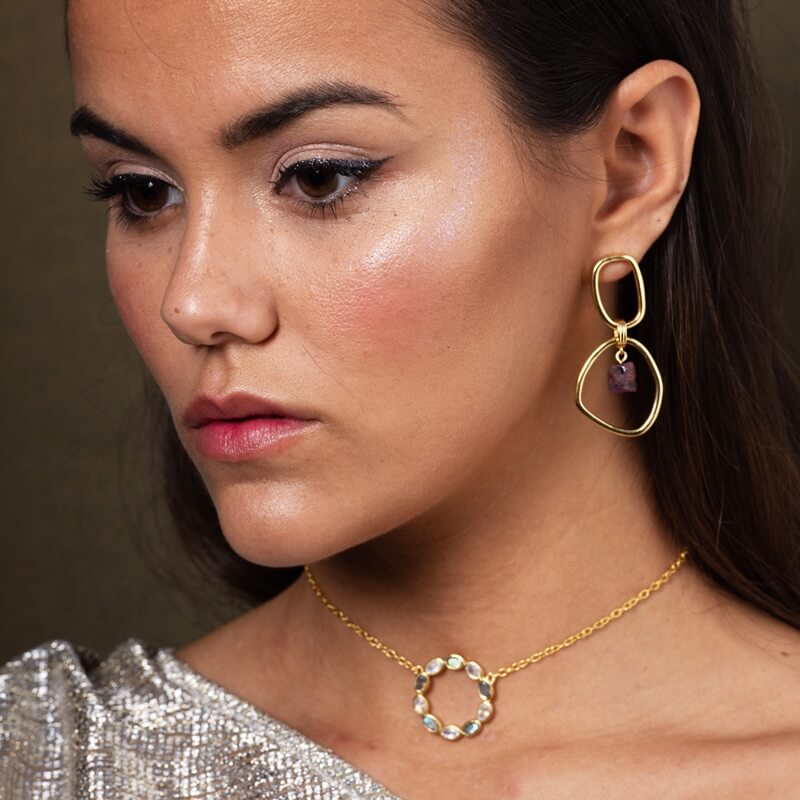 Modelo con aros dorados y piedra granate de lavani jewels