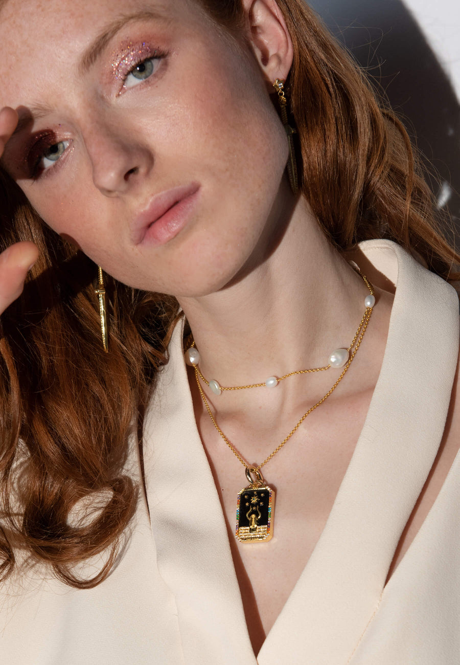 foto de modelo con combinación de joyas formadas por colgante de carta de tarot la estrella, collar con perlas barrocas y pendientes de espada bañados en oro de 18 quilates