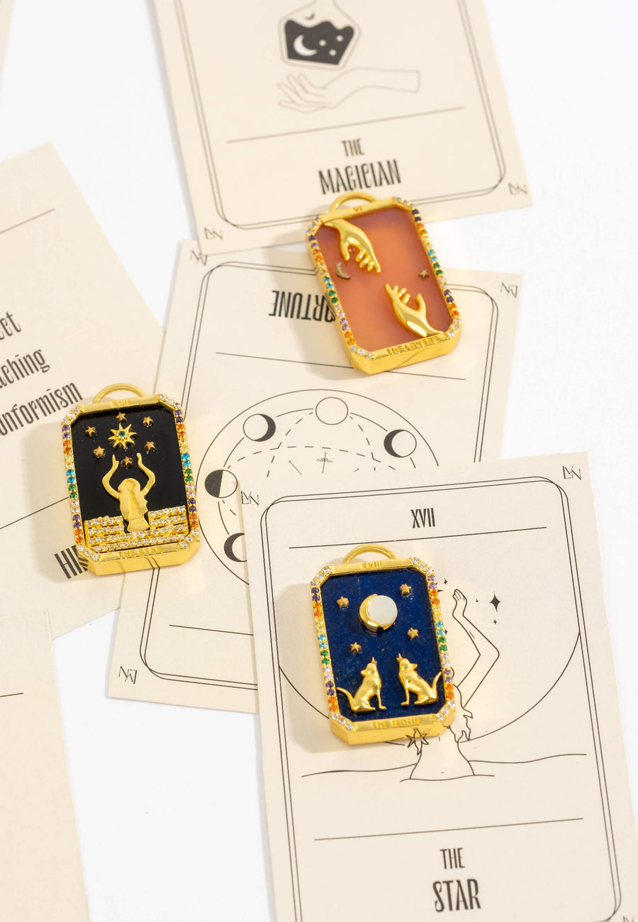 foto de bodegón de charms de colgantes de cartas del tarot con piedras naturales semiprecosas y detalles tallados a mano