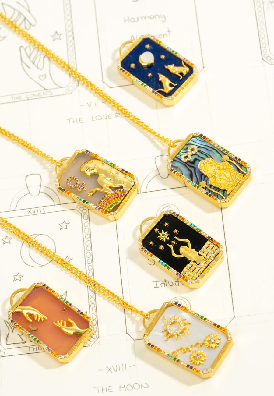 foto de bodegón de colgantes de cartas del tarot bañados en oro de 18 quilates con piedras naturales semipreciosas