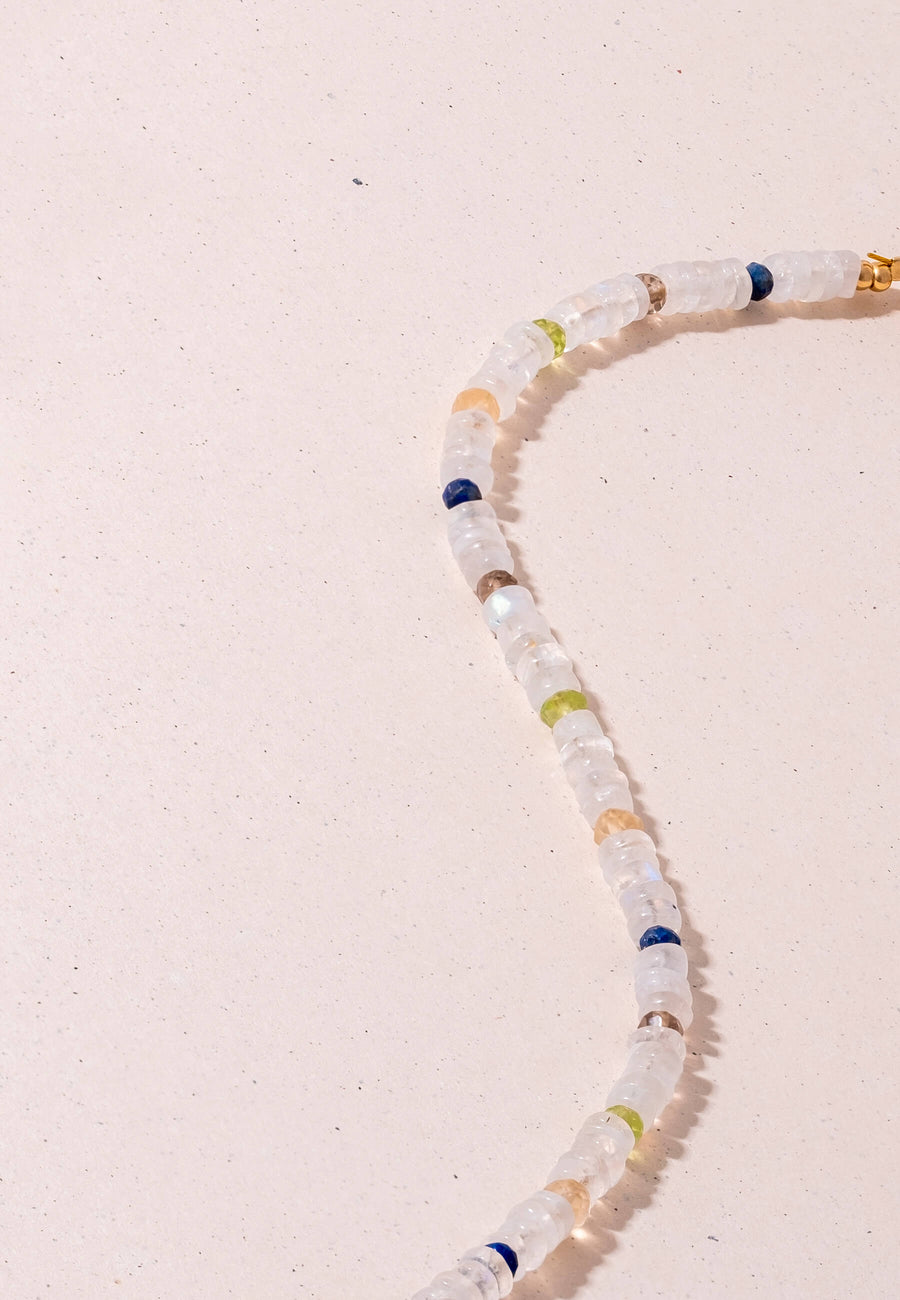Zoom de collar de Piedra Luna de colores hecho con cuentas de la piedra Luna blanca sobre fondo rosa claro