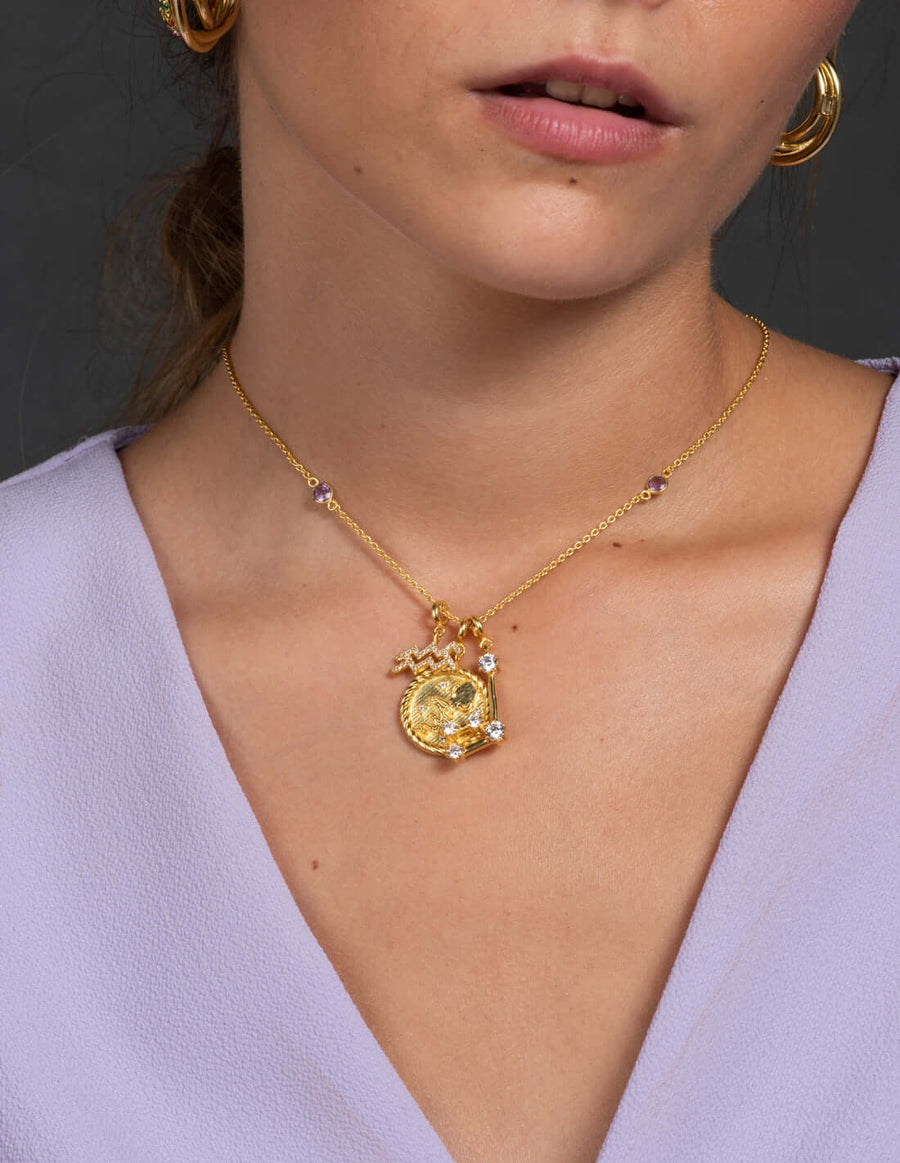 modelo con cadena dorada y charms simbolo zodiaco