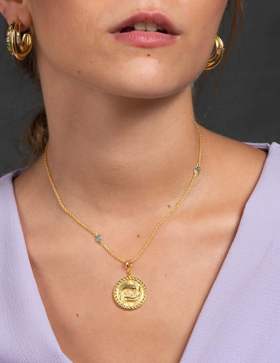 modelo luciendo collar con moneda dorada simbolo zodiaco